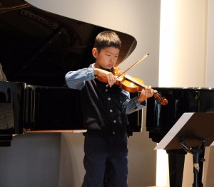 Child plays violin at violin recital in Beverly Hills