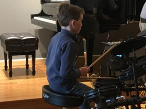 Child plays drums at the music recital